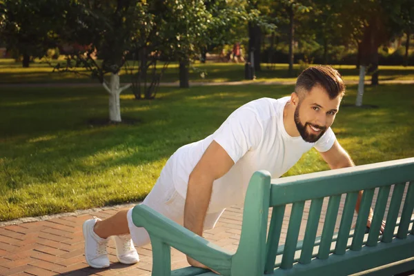 Schöner sportlicher Mann macht Liegestütze im Park an sonnigem Tag — Stockfoto