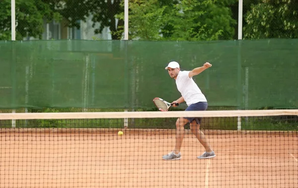 Mladý muž hrát tenis na kurtech — Stock fotografie