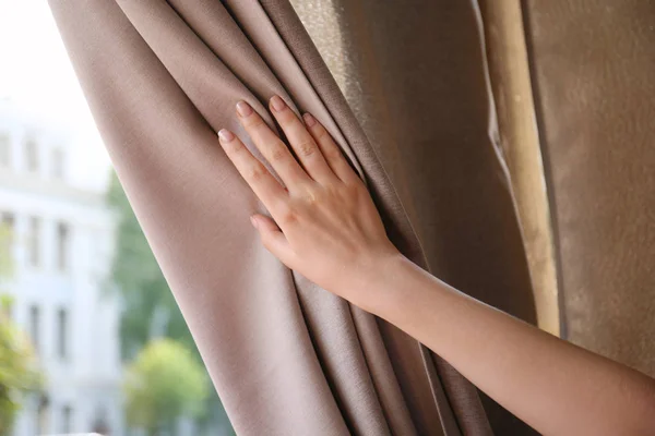 Mulher tocando cortina marrom dentro de casa, close-up — Fotografia de Stock