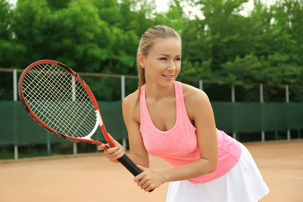 Молодая женщина играет в теннис на корте — стоковое фото