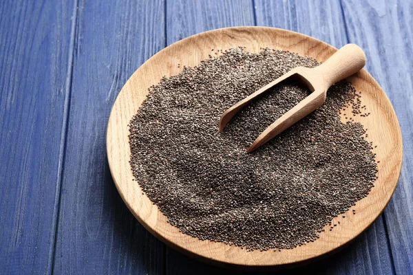 Wooden plate with chia seeds and scoop on table — Stock Photo, Image