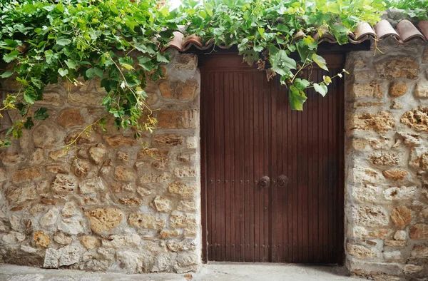 Old stone wall with large wooden door — Stock Photo, Image