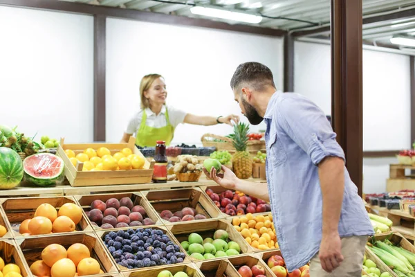 Junger Mann sucht Obst auf dem Markt aus — Stockfoto