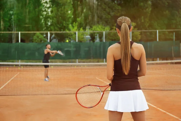 Mujer joven y hombre jugando al tenis en la cancha — Foto de Stock
