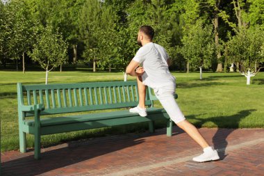 Sportif adam parkta güneşli günde germe