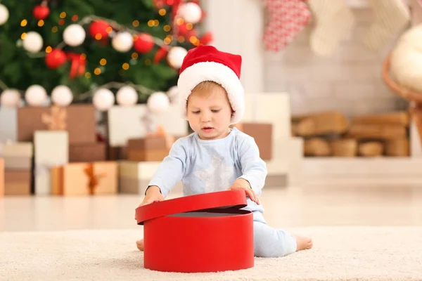 Niedliches kleines Baby mit Geschenkbox im weihnachtlich dekorierten Zimmer — Stockfoto