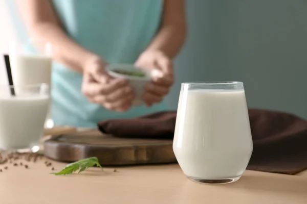 Glass with hemp milk and blurred woman