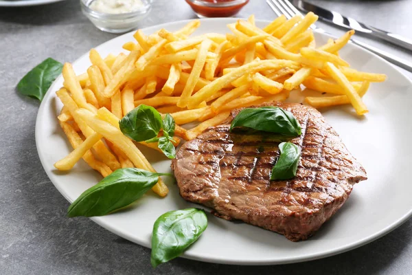 Placa con delicioso bistec y papas fritas — Foto de Stock