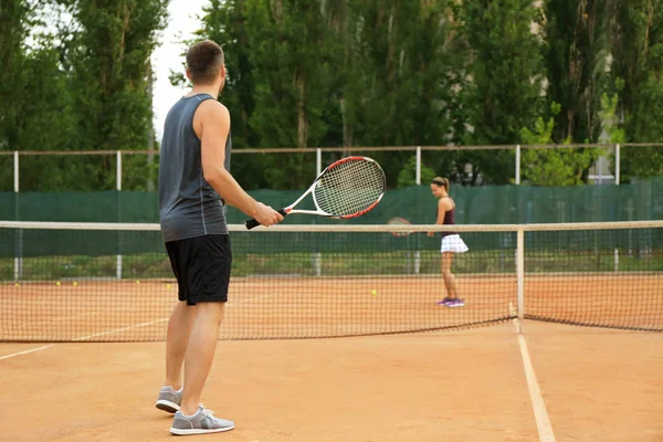 Mladý muž a žena hrát tenis na kurtu — Stock fotografie