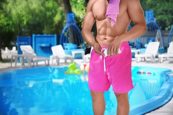Aantrekkelijke man toepassing van zonnebrandcrème op huid in de buurt van zwembad — Stockfoto