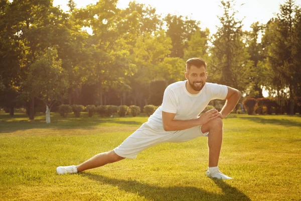 Sportieve man die zich uitstrekt in park op zonnige dag — Stockfoto