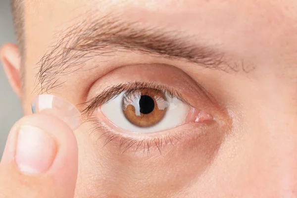 Молодий чоловік кладе контактну лінзу йому в очі — стокове фото