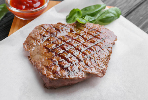 Delicious grilled steak on waxed paper in kitchen