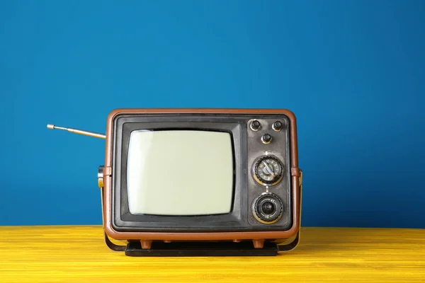 Vintage telewizji na drewnianym stole w pobliżu kolor ściany — Zdjęcie stockowe