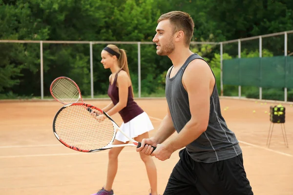 Young man and woman playing tennis on court — Stock Photo, Image