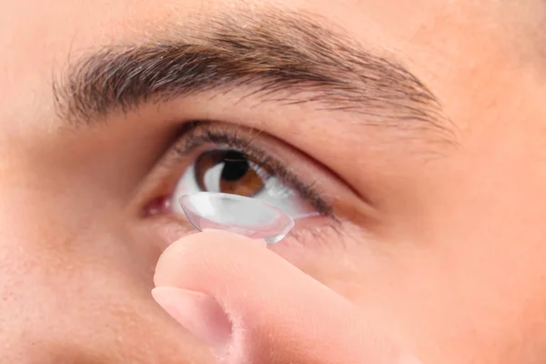 Young man putting contact lens, closeup — Stock Photo, Image