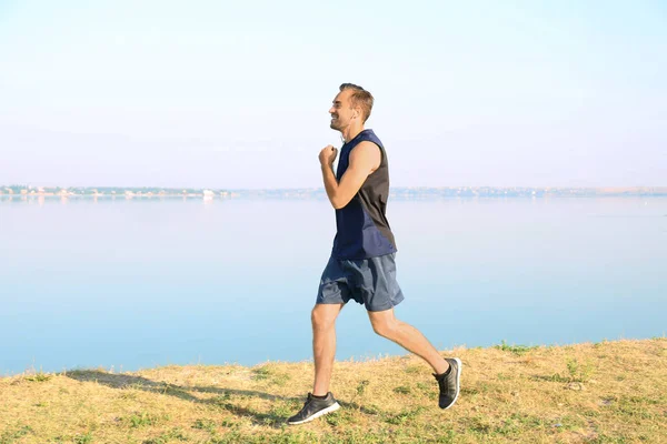 Handsome young man running outdoors — Stock Photo, Image