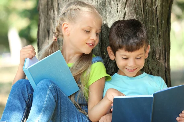 Aranyos kis gyerekek fa, a park közelében, olvasás — Stock Fotó