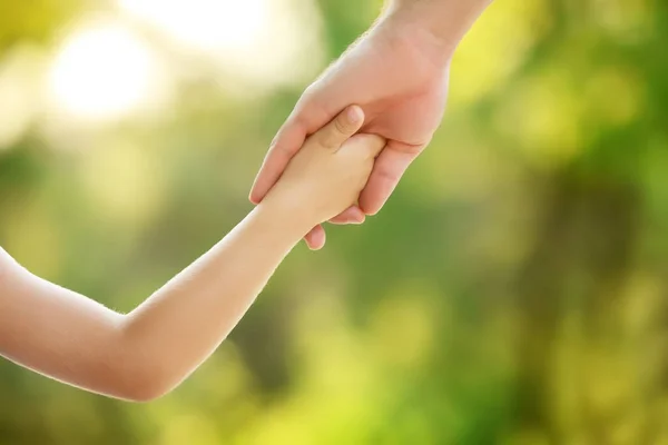 Uomo che tiene per mano suo figlio nel parco nella giornata di sole, primo piano — Foto Stock