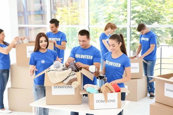 Team of teen volunteers collecting donations in cardboard boxes indoors — Stock Photo, Image