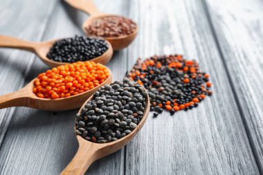 Ahşap arka plan üzerinde farklı mercimek kaşıklarla