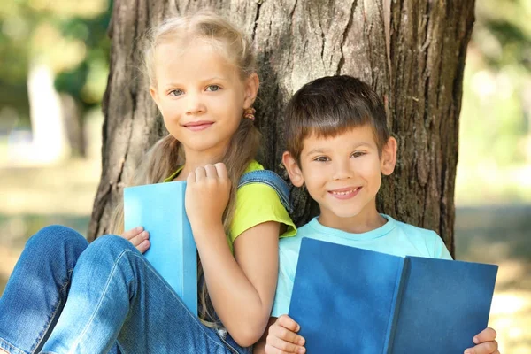 公園内の木の近くの本を読んでかわいい子供たち — ストック写真