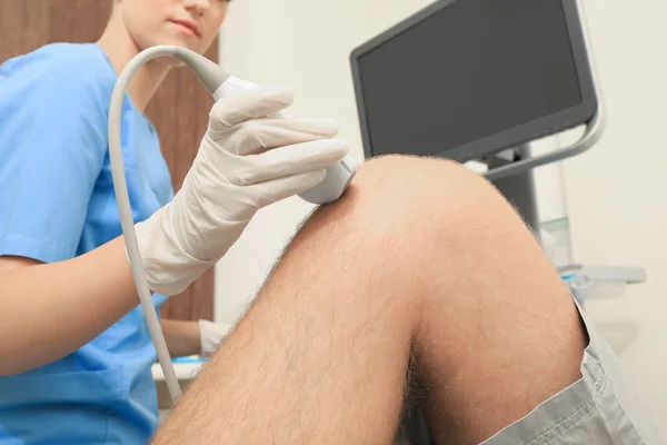 Dokter geleidende echografie onderzoek van de knie van de patiënt in kliniek — Stockfoto