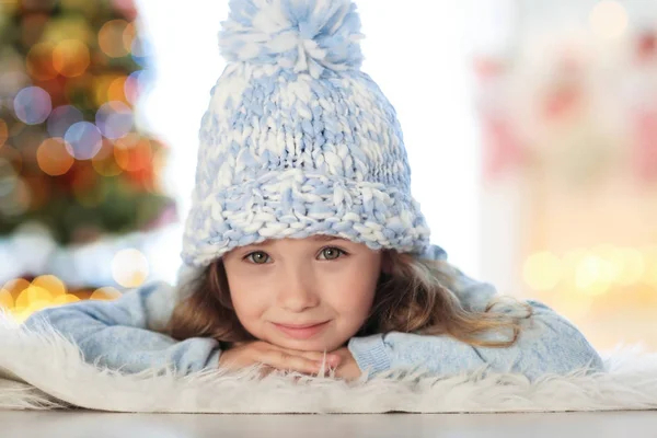 Gelukkig klein meisje in de hoed liggend op tapijt thuis — Stockfoto
