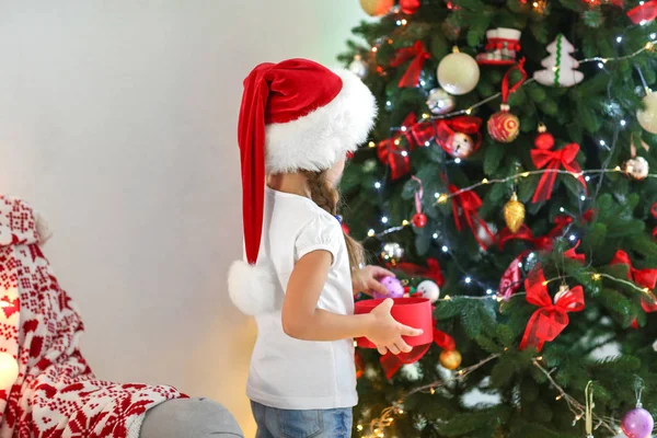 Ładna Dziewczynka Santa Hat Dekorowanie Choinki Domu — Zdjęcie stockowe