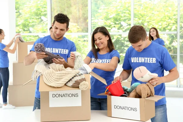 Ομάδα εφήβων εθελοντών συλλέγοντας δωρεές σε κουτιά από χαρτόνι σε εσωτερικούς χώρους — Φωτογραφία Αρχείου