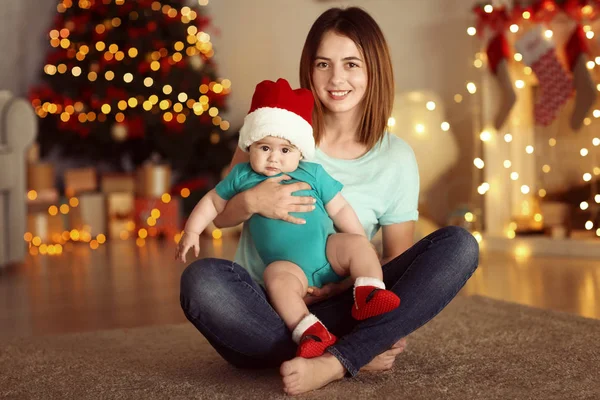 Jovem mãe feliz com bebê pequeno em decorado para a sala de Natal — Fotografia de Stock