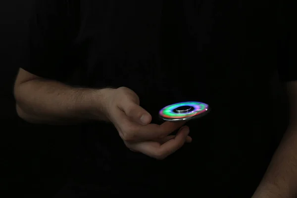 Man rolling modern luminous spinner on dark background — Stock Photo, Image