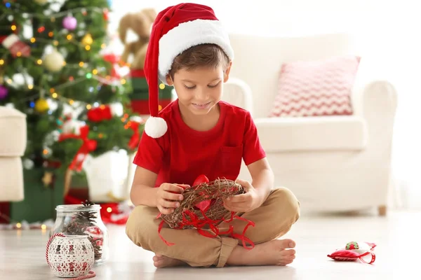 Garçon mignon décorant couronne de Noël sur le sol — Photo