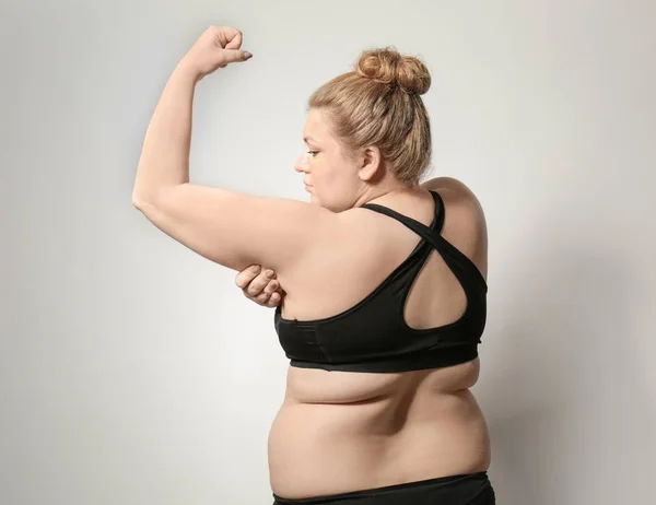 Mulher tocando gordura em seu braço contra fundo claro. Conceito de perda de peso — Fotografia de Stock