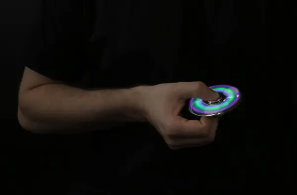 Man rolling modern luminous spinner on dark background — Stock Photo, Image