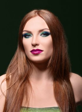Güzel kızıl saçlı kadın koyu arka plan üzerinde parlak yeşil makyaj ile