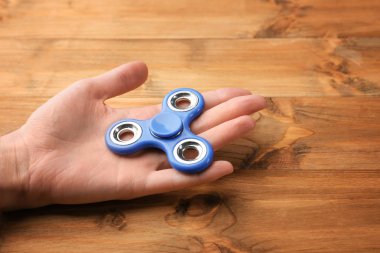 Modern spinner ahşap arka plan üzerinde tutan kadın