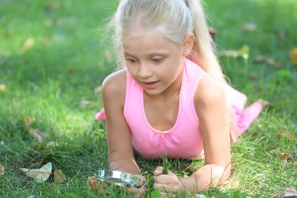 Schattig Klein Meisje Met Vergrootglas Liggen Groen Gras Park — Stockfoto