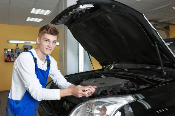 Молодой механик ремонтирует машину в автомастерской — стоковое фото