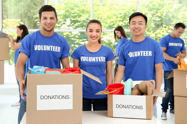 Equipo de voluntarios adolescentes de pie cerca de la mesa con cajas de donación en el interior — Foto de Stock