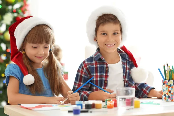 Niedliche Kinder malen Bilder für Weihnachten am Tisch — Stockfoto