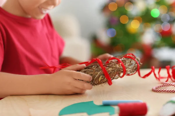 Leuke jongen verfraaien van de kroon van Kerstmis op tafel — Stockfoto