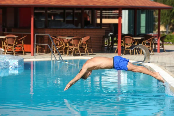 Young man jumping in swimming pool at resort — Stock Photo, Image