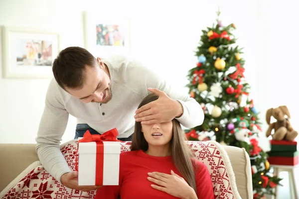 Giovane uomo rendendo sorpresa di Natale per la sua ragazza a casa — Foto Stock