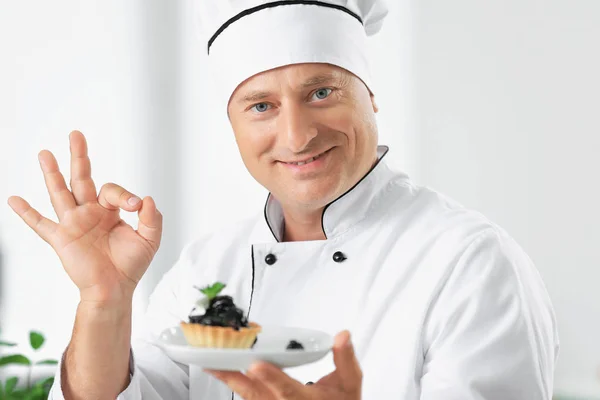 Male chef holding plate with dessert in kitchen — Stock Photo, Image