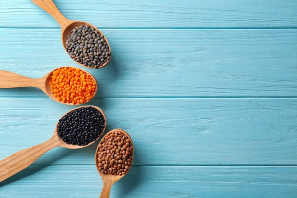Ahşap arka plan üzerinde farklı mercimek kaşıklarla