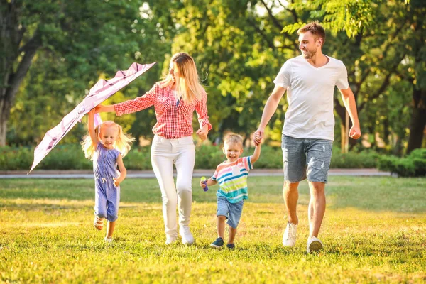 Счастливая семья играет с воздушным змеем в парке в солнечный день — стоковое фото