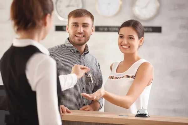 Casal jovem recebendo chave do quarto de hotel na recepção — Fotografia de Stock