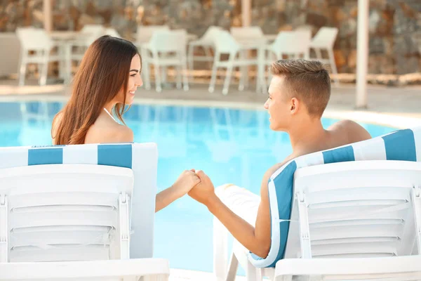 リゾートのスイミング プールの近く休んで幸せな若いカップル — ストック写真