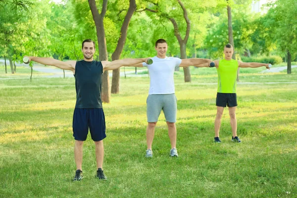 Jóvenes deportistas con campanas mudas haciendo ejercicio al aire libre — Foto de Stock